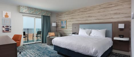 A hotel room with a large bed, a desk, a chair, a balcony with a view, and a wall with a patterned design.