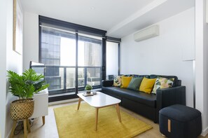 Relax in this stylish living room with a city view, featuring a sofa, coffee table, and potted plant.