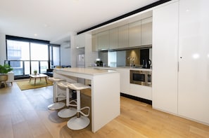 Enjoy cooking in this kitchen with a sleek island, bar stools, and ample counter space, featuring integrated appliances and a view of the city.