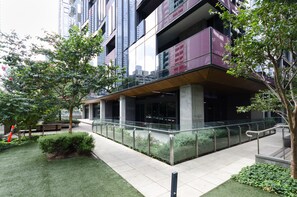 Stunning urban building with a unique design, featuring a cantilevered section and a beautifully maintained garden area.