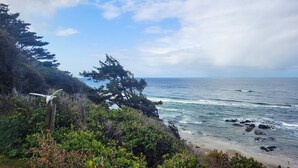 A coastal landscape with a view of the ocean, a wooden structure, and dense greenery. - Ocean Front A Frame with Spectacular Views! Dog Friendly! Fireplace! (Florence)