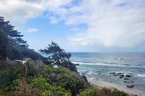 A coastal landscape with a view of the ocean, a wooden structure, and dense greenery.