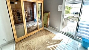 Een kamer met een schuifglazen deur naar een balkon, een houten garderobe en een blauwe prullenbak.