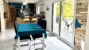 Een moderne keuken met een eethoek, een schuifdeur naar een terras buiten, en uitzicht op groen.