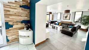 Een moderne woonkamer met een pooltafel, een leren bank en een potplant.