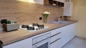 Cozinha moderna com painel de madeira, fogão embutido, pia e um pequeno armário.