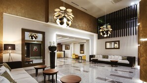 Um hall amplo com design moderno, apresentando um sofá grande, uma mesa de centro e uma área de estar com cadeiras.