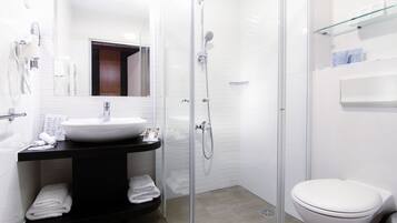 Un baño moderno con ducha envuelta en vidrio, lavamanos blanco y retrete.