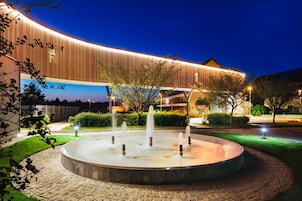 A modern building with a curved facade and a circular water feature in front.