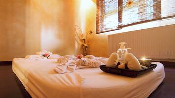 A neatly made bed with towels, a tray with toiletries, and a vase with flowers.