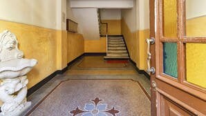 A hallway with a staircase, a decorative wall sculpture, and a door with a green panel. - Central & Cozy Apartment by Wonderful Italy (Genova)