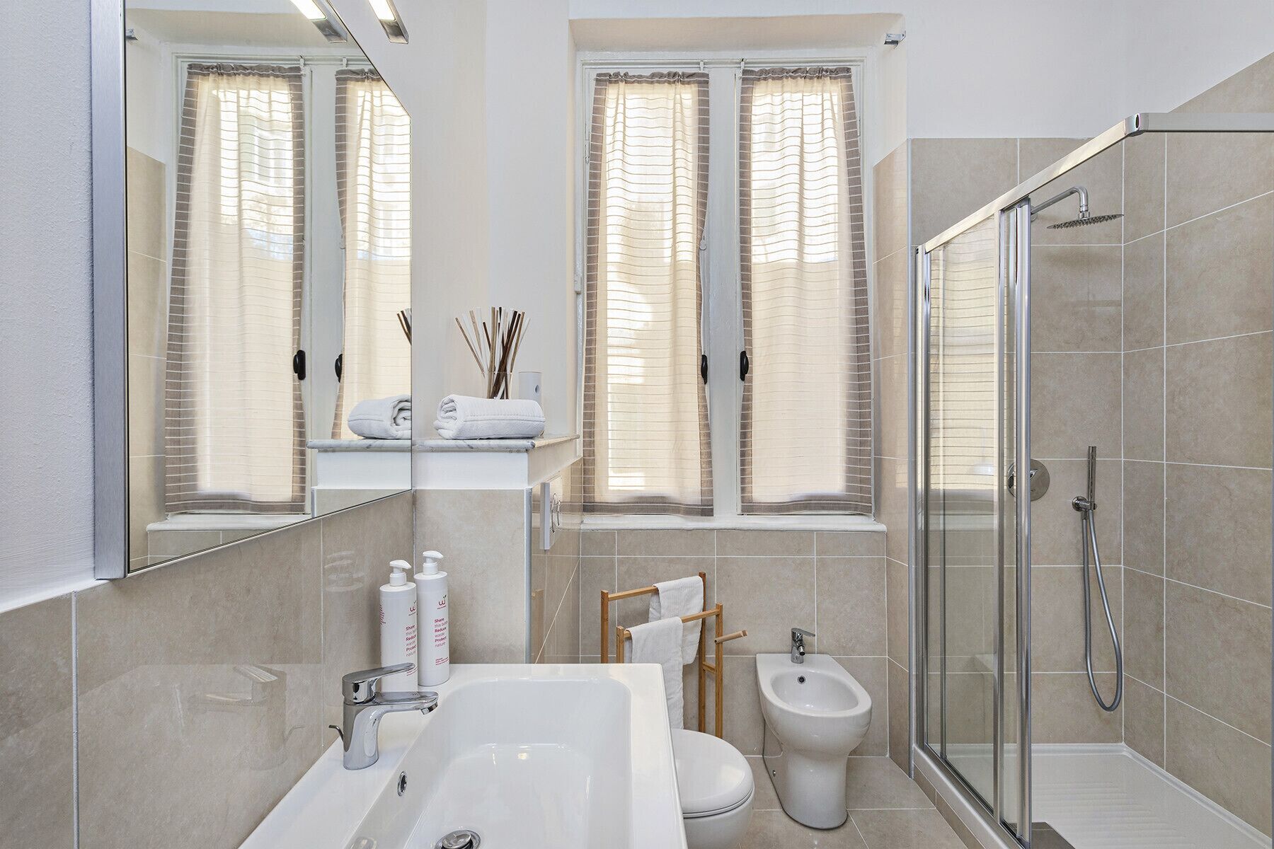 A modern bathroom with a large bathtub, a toilet, a bidet, and a glass-enclosed shower area.