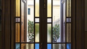 A view through a window with multiple panes, revealing a building with balconies and greenery outside. - Central & Cozy Apartment by Wonderful Italy (Genova)