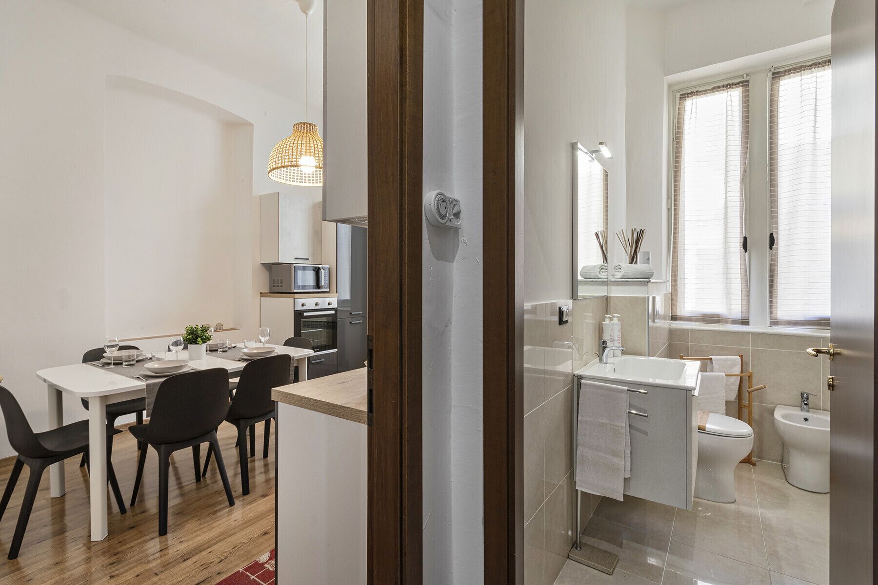Una cocina moderna con microondas, horno y comedor con sillas y mesa.