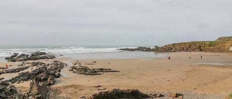 Een strand met rotsformaties en een helder uitzicht op de oceaan.