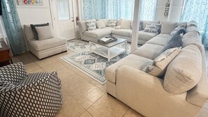 A spacious living room with a beige sofa set, a patterned rug, and a coffee table.