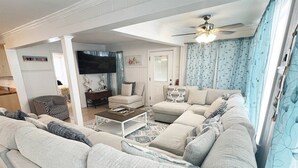 A modern living room with a large sectional sofa, a coffee table, and a television.