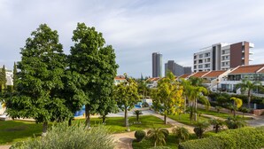 A landscaped courtyard with trees, a pathway, and modern buildings in the background. -  Bay View Gardens Apts with Pool by TrulyCyprus (Limassol)