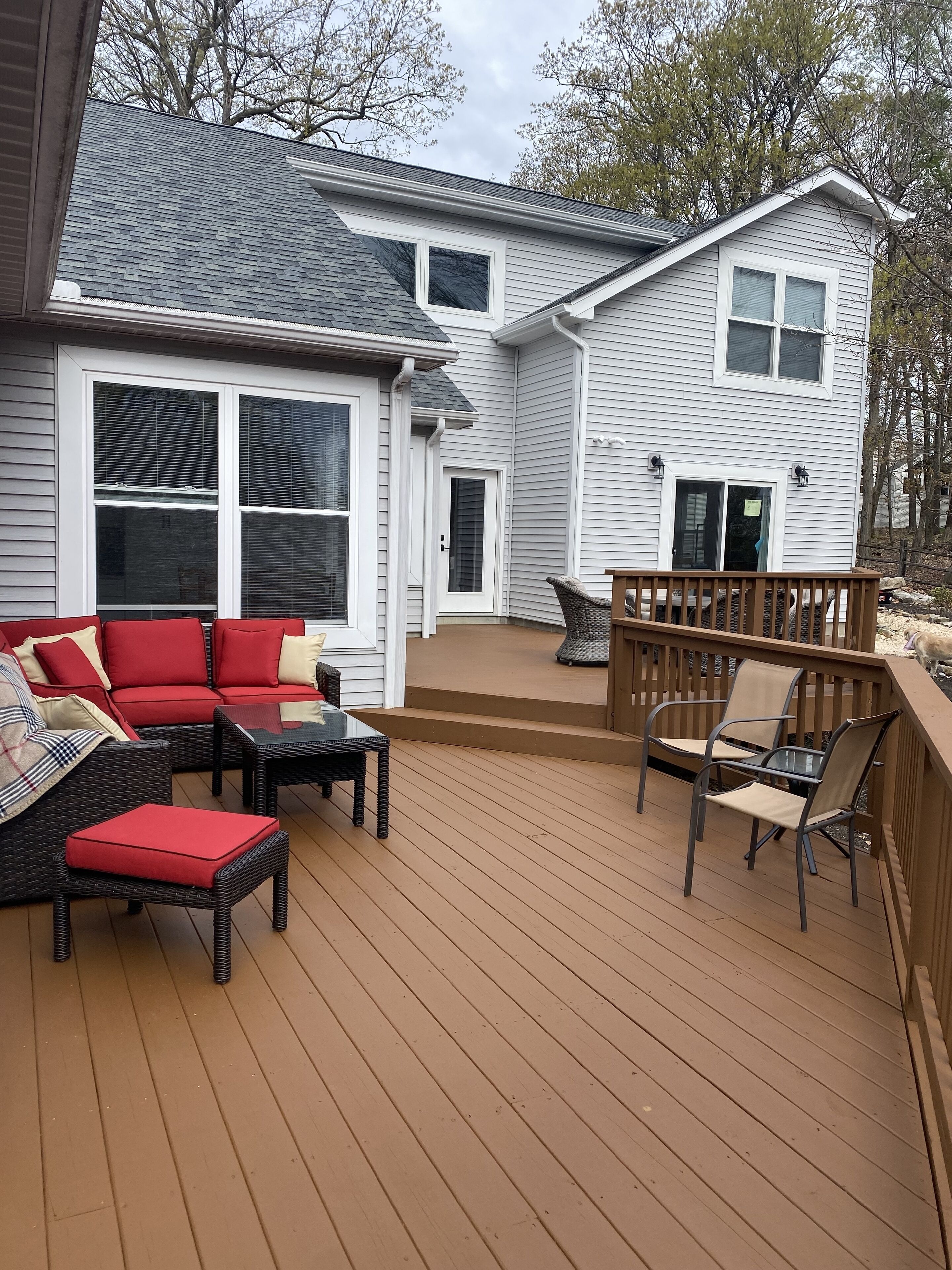 Une terrasse avec mobilier d’extérieur, un patio couvert et une maison à l’extérieur grise et aux ornements blancs.