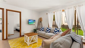 Ett vardagsrum med en soffa, ett litet träbord, en tv och utsikt över omgivningen.
