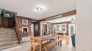 A spacious dining area with a wooden table and benches, a staircase, and a view of the outdoors.