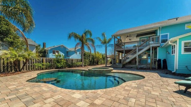 A backyard with a swimming pool, a wooden fence, and a house with a balcony.