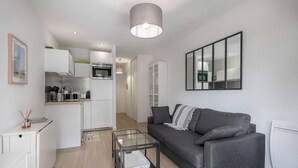 En modern lägenhet med ett kök, en grå soffa och ett soffbord i glas.