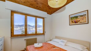 Un dormitorio con un ventanal grande, techo de madera y un cuadro en la pared.