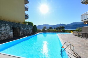 Une piscine avec un mur en pierre et une vue sur les montagnes.