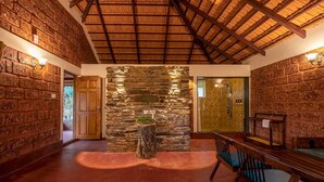 A rustic interior with stone walls, a wooden ceiling, and a seating area with benches. - Gudlu (Mudigere)