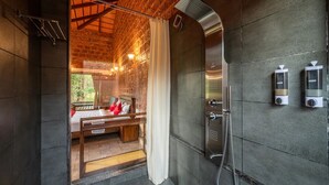A modern bathroom with a shower, a bed, and a view of a wooden cabin. - Gudlu (Mudigere)