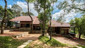 A two-story building with a red-tiled roof, stone walls, and a stone pathway leading to the entrance. - Gudlu (Mudigere)