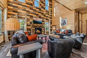Ein rustikales Holzhaus-Interieur mit Kamin, Ledersofas und einem großen Fenster.