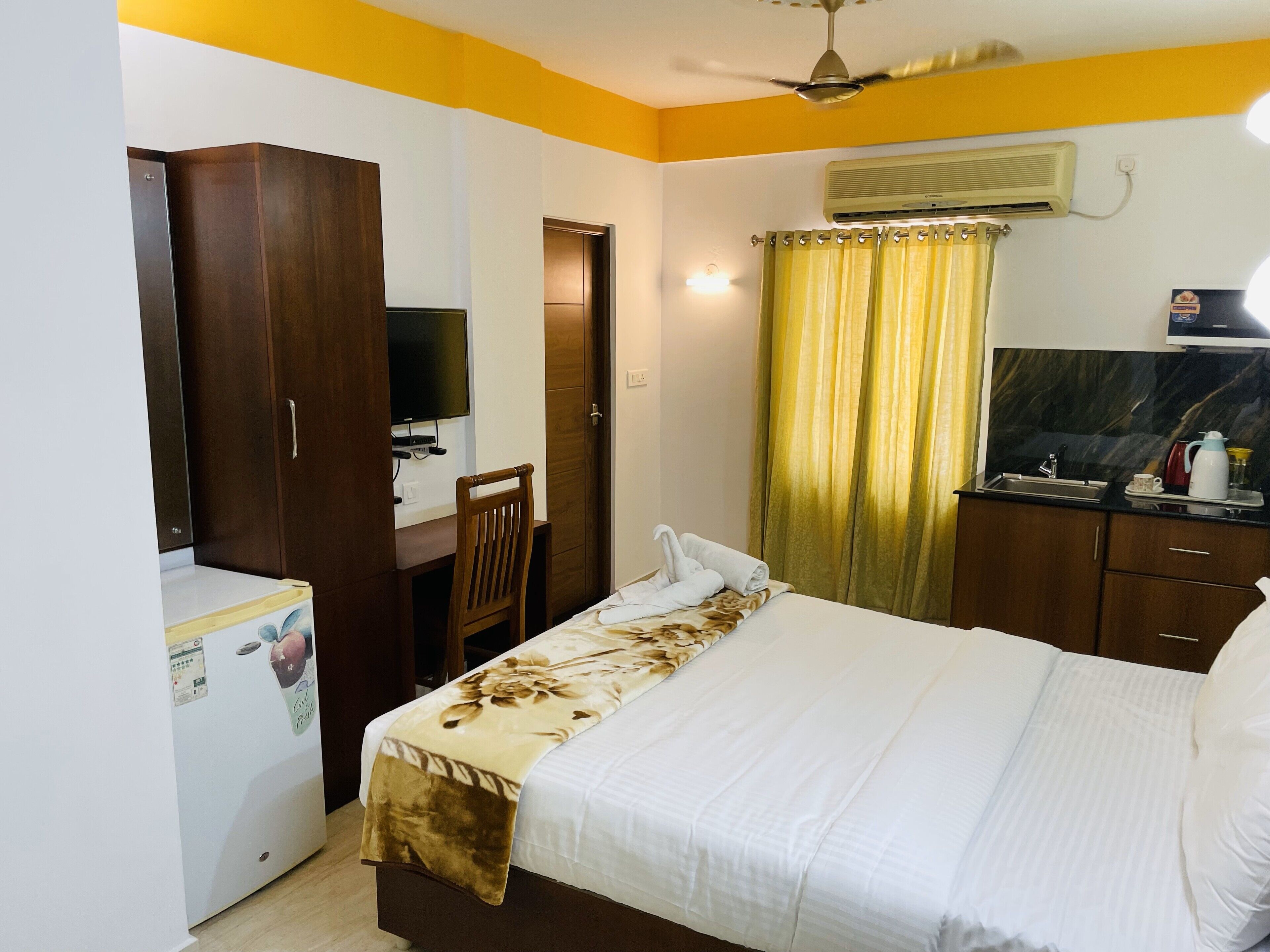 Une chambre d’hôtel équipée d’un lit, d’un bureau, d’une armoire, d’une télévision et d’une kitchenette.