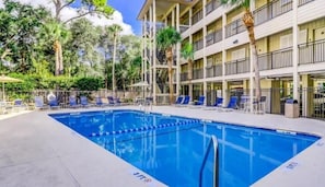 Relax by the hotel's large pool surrounded by lush greenery and lounge chairs.