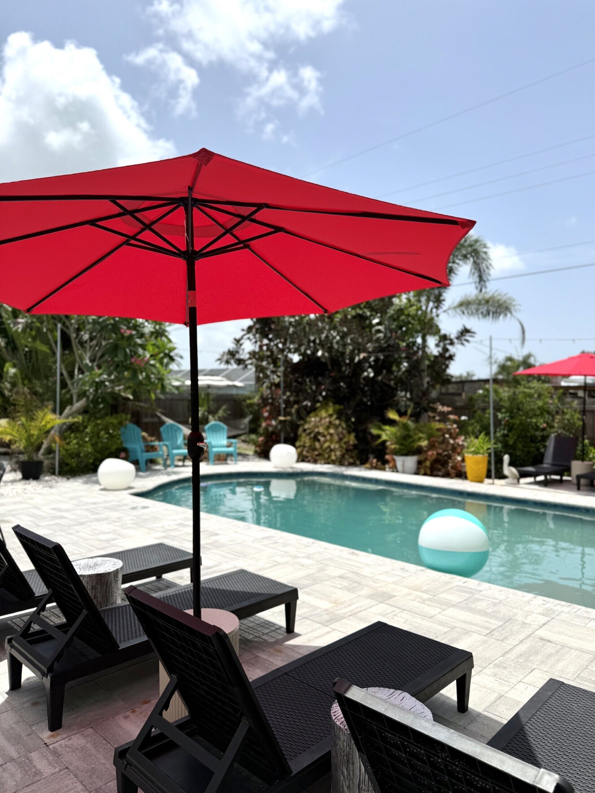 A poolside area with lounge chairs and a red umbrella.