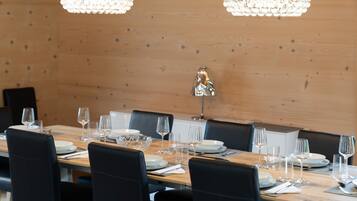 A dining area with a wooden table set for a meal, black chairs, and two crystal chandeliers.