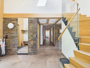 A modern interior with a stone accent wall, a wooden staircase, and a glass railing. - Chalet Alia and Apartments-Grindelwald by Swiss Hotel Apartments (Grindelwald)