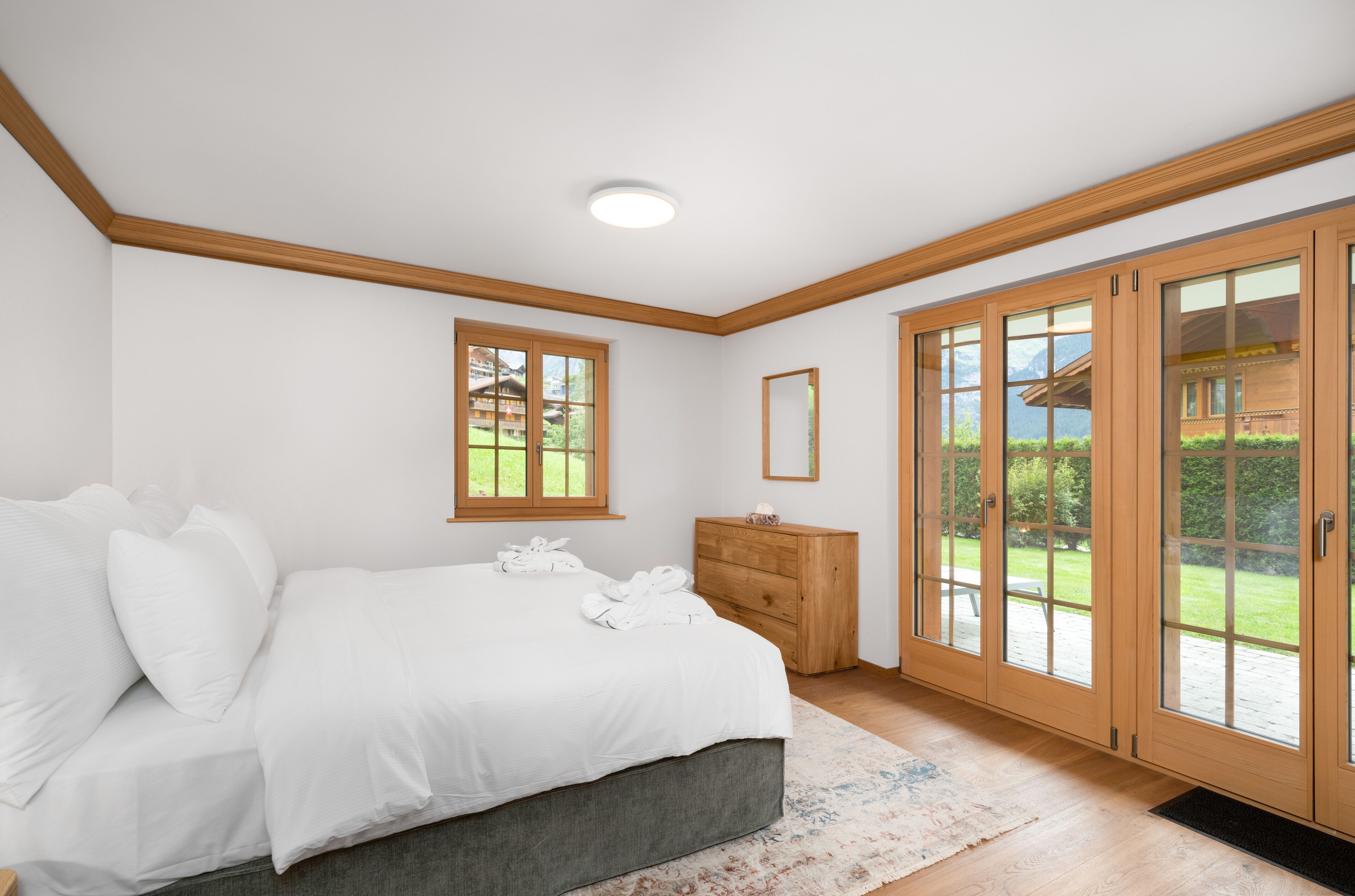 A bedroom with a bed, a dresser, and a large sliding glass door leading to a patio.