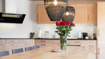 Une cuisine moderne avec des meubles en bois, un îlot central agrémenté d’un vase de roses rouges et des luminaires suspendus.