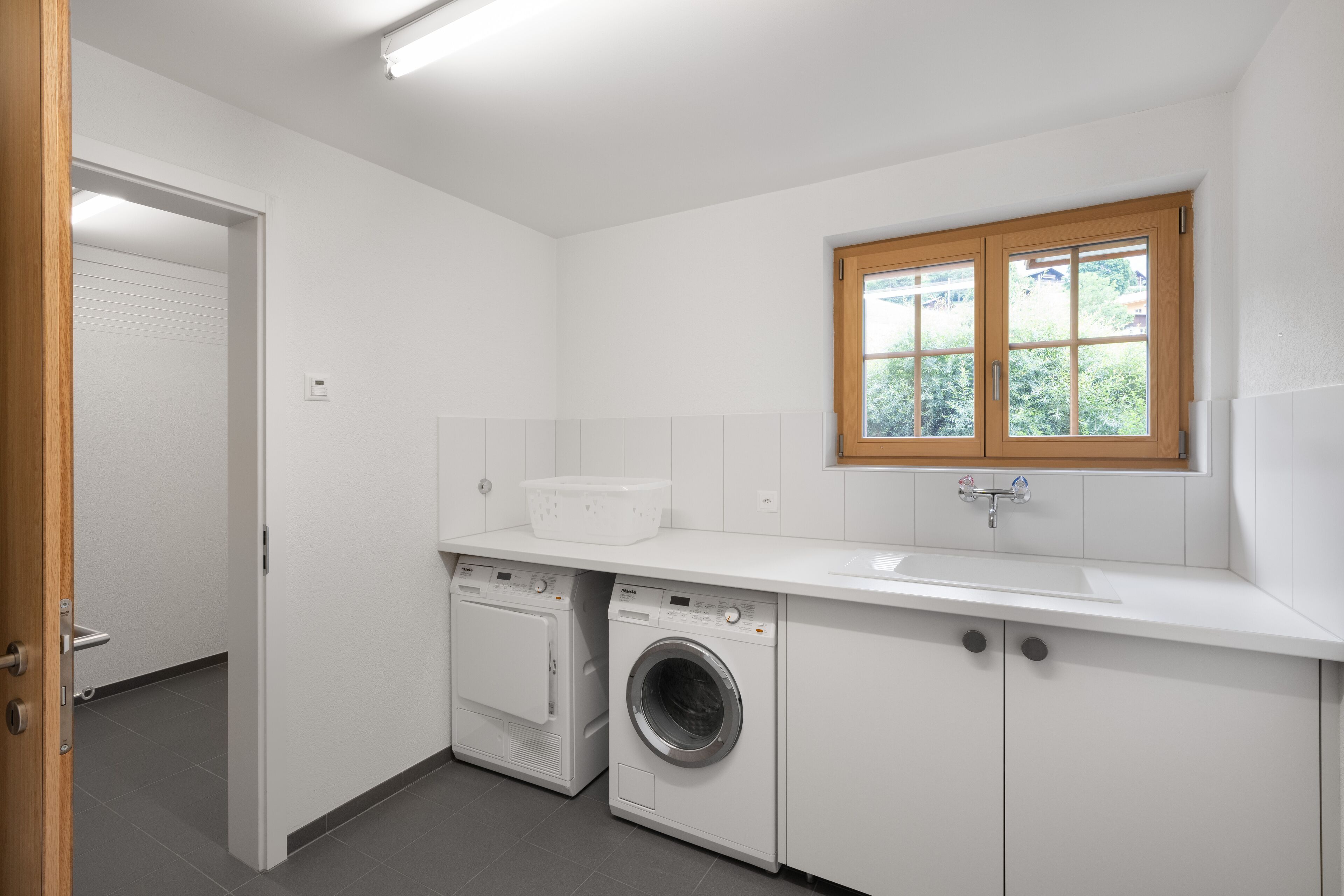 Une petite buanderie équipée d’un lave-linge, d’un sèche-linge et d’un évier.