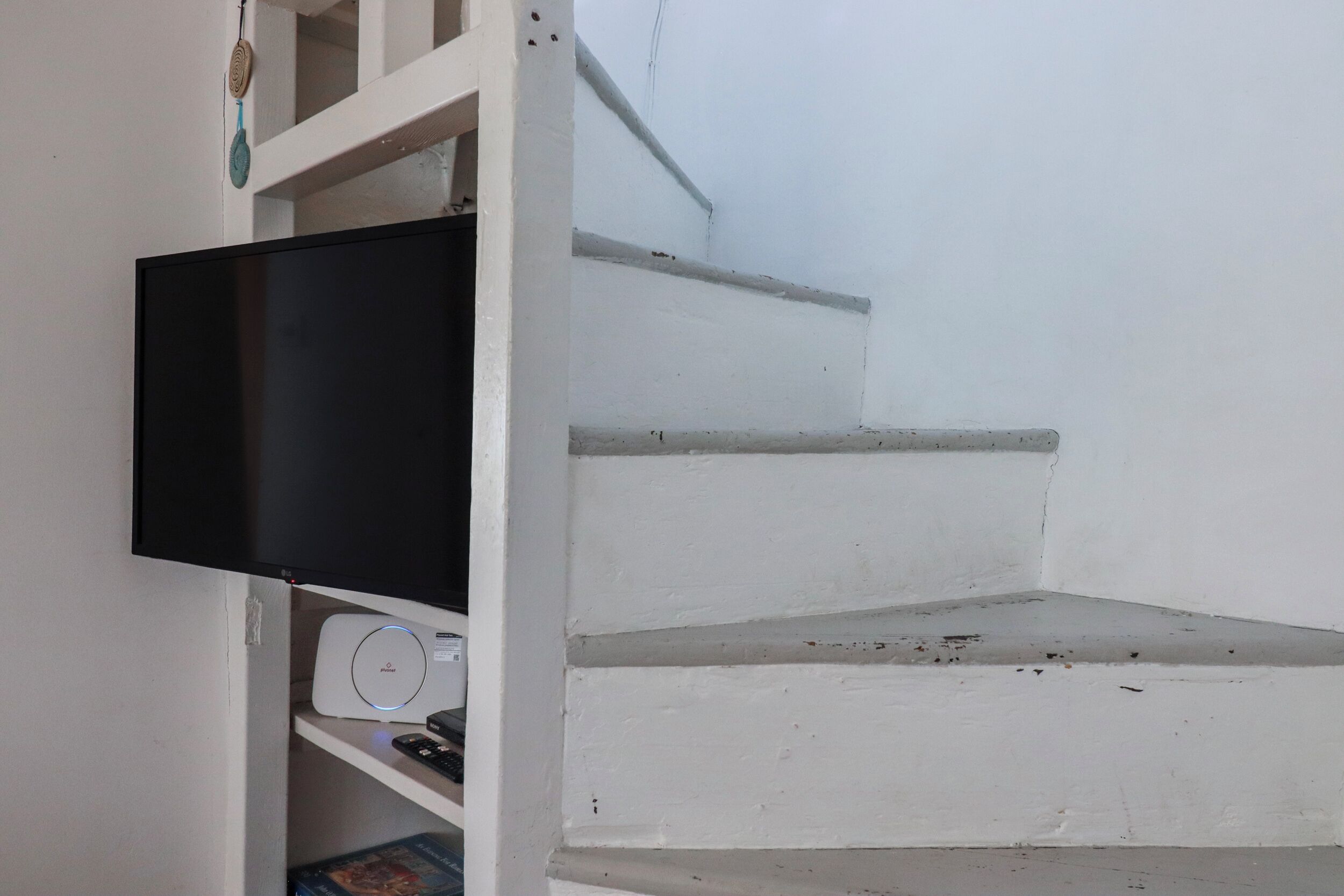 Una escalera blanca con un televisor de pantalla plana montado en una pared blanca.