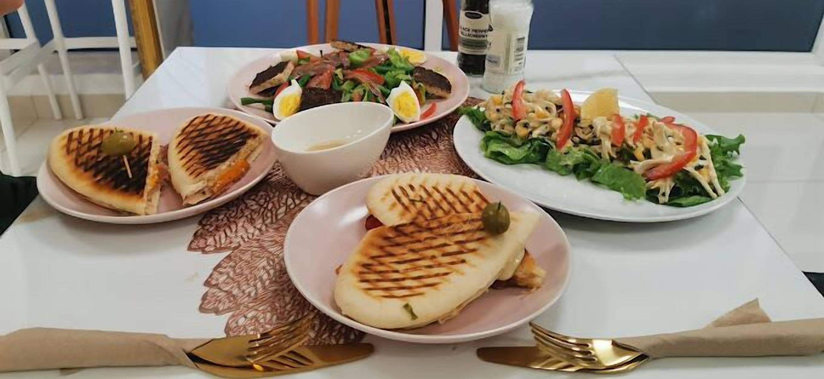 Una mesa con platos de comida, incluyendo preparaciones a la parrilla y ensaladas.