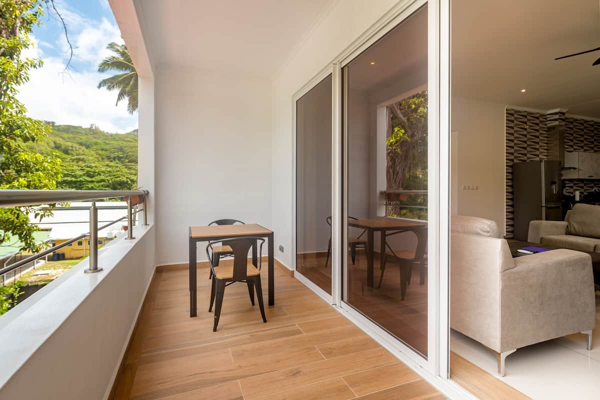 Ein Balkon mit Holzboden, einem Tisch und einem Stuhl.
