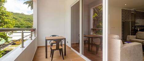 A balcony with a wooden floor, a table, and a chair.
