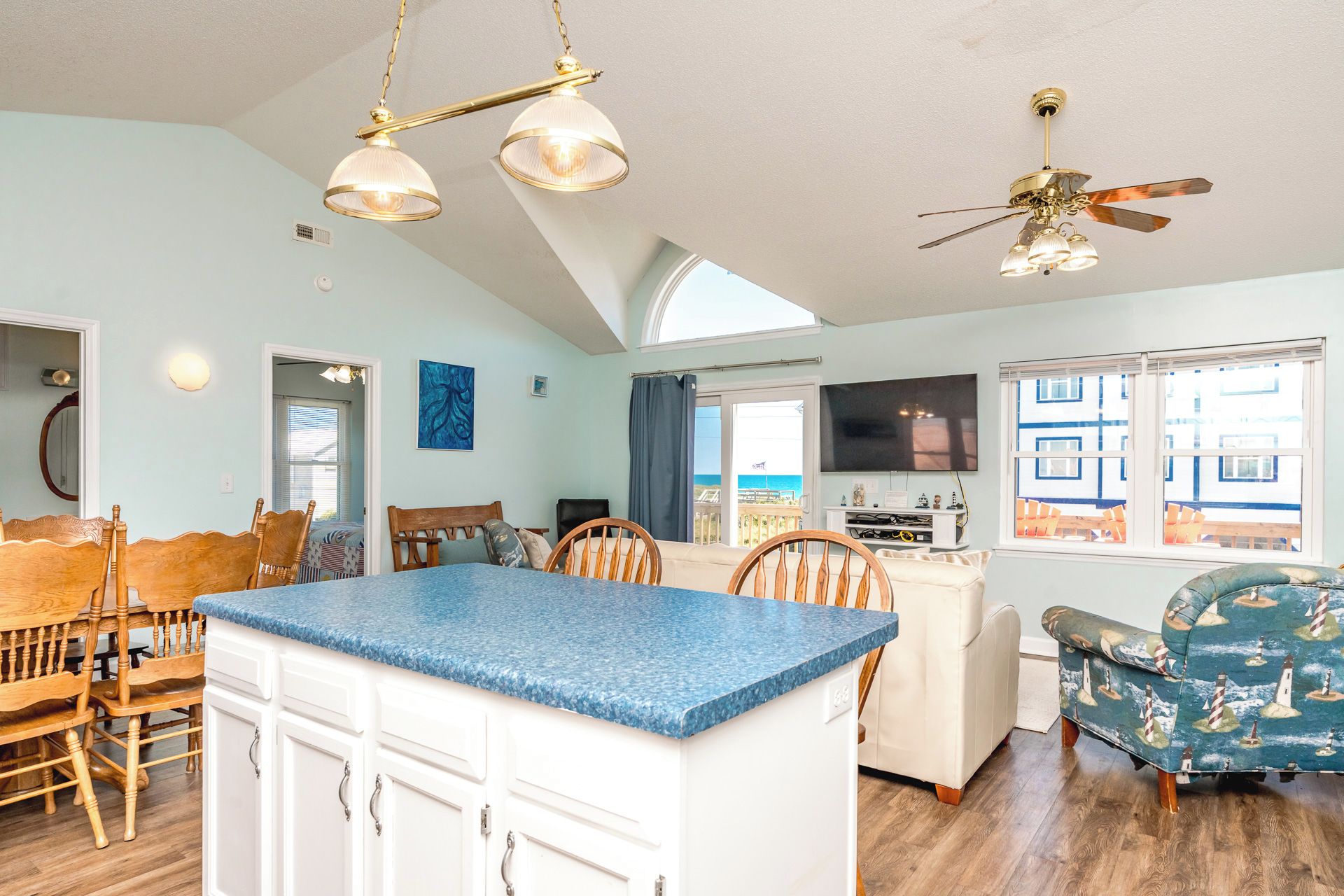 A spacious living area with a large island, a ceiling fan, and a view of the outside.