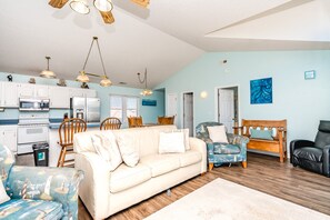 A living room with a beige sofa, a patterned armchair, and a blue armchair. - No Regrets - 4 BR home in the heart of Surf City! Dog Friendly! (Surf City)