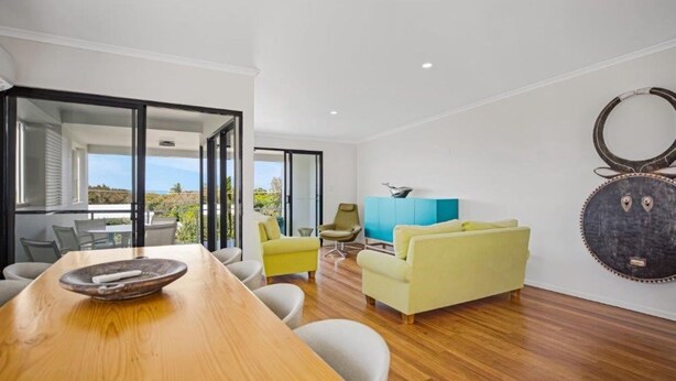 A modern living room with a wooden dining table, yellow sofa, and a blue cabinet. - Ocean View Villa Marco (Marcus Beach)