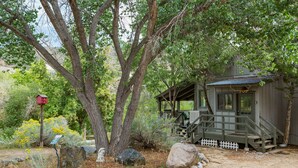 A rustic cabin with a porch, surrounded by trees and rocks. - Pet Friendly Rustic Cabin on the Animas River -  6 Min. to Downtown Durango (Durango)