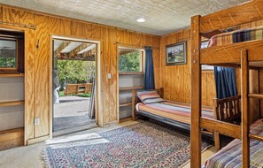 A wooden cabin with a bunk bed, a bench outside, and a patterned rug.